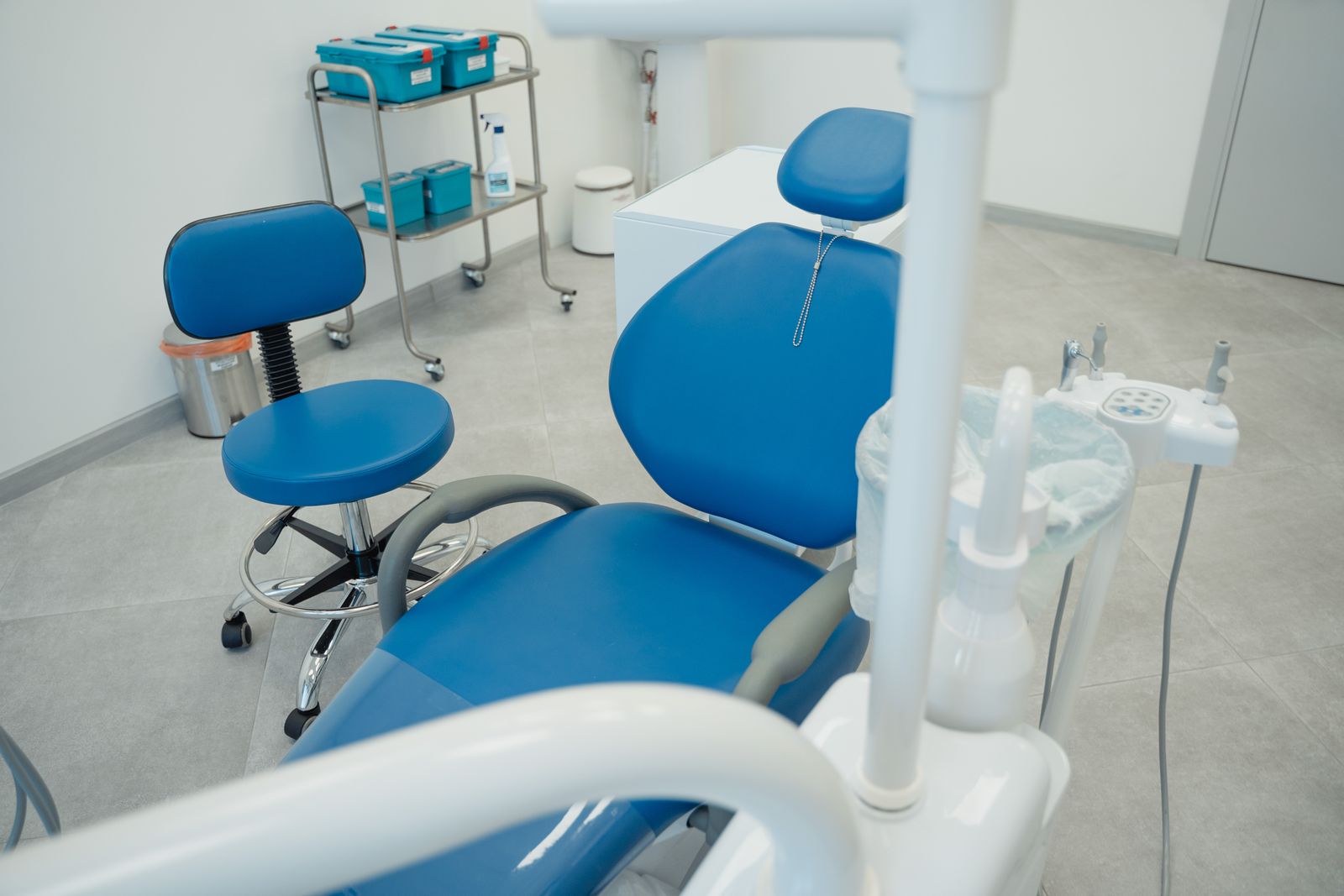 A treatment room with a blue dental chair and overhead light