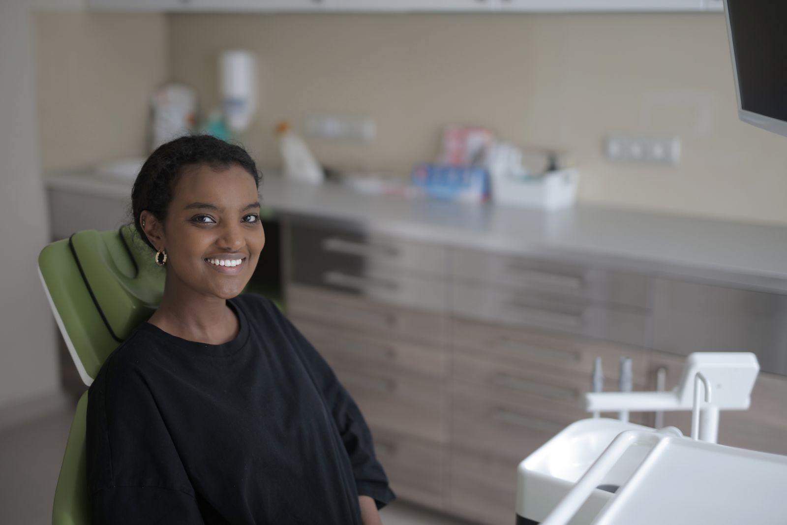 A smiling patient sitting in a dental chair in a bright treatment room