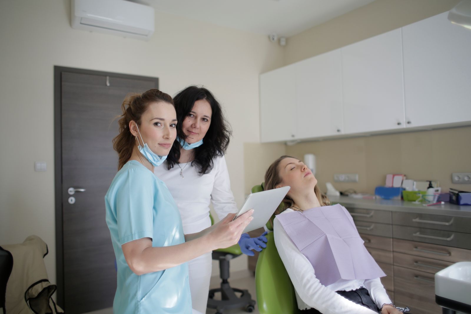 Two team members showing a tablet to a patient resting in a treatment chair